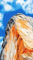 Majestic Mountain Landscape A Stunning View of a Rocky Cliff against a Bright Blue Sky with Fluffy Clouds. The Abstract Texture and Colors Create a Breathtaking Natural Scene. photo