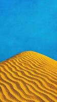 Golden Desert Dune under a Vivid Blue Sky A Minimalist Landscape Photography photo