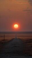 A breathtaking sunset paints the vast landscape with warm hues, illuminating a lonely road stretching into the horizon. A serene and captivating view of the golden hour. photo