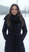 A woman in a black coat standing in the snow photo