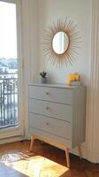 Sunlit Parisian Apartment Interior Grey Chest of Drawers, Sunburst Mirror, and City View photo