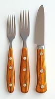 A high resolution image showcases an elegant set of cutlery a knife and two forks. The wooden handles, with their rich, rustic te photo