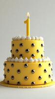 A delightful first birthday cake, a two layered masterpiece in sunny yellow with elegant silver accents. The single lit candle add photo