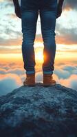 A breathtaking landscape photograph showcasing a solitary figure standing atop a mountain peak, gazing at a mesmerizing sunset ove photo