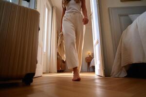 Woman in Beige Pants Walking Barefoot in Hotel Room, Enjoying a Calm and Peaceful Vacation. Travel, Journey, and Relaxation Concep photo