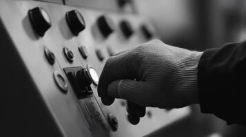 un trabajadores mano opera un industrial máquinas controlar panel. el monocromo imagen enfatiza el texturas y detalles de el mach foto