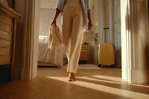Woman Walking Barefoot in a Luxurious Hotel Room, Ready for Travel. Sunlight streams through the windows, illuminating the elegan photo