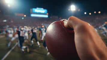 Gridiron Glory A Night Game Under the Stadium Lights. A of a Players Hand Holding an American Football, with a Blurred Backgroun photo