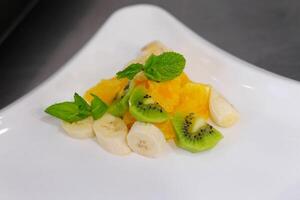 fruit salad kiwi banana orange White bowl of fresh fruit salad isolated on white background. Healthy summer meal photo