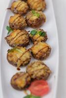 Stuffed mushrooms with cream cheese, bread crumbs and nuts on plate over wooden background. Top view, flat lay photo