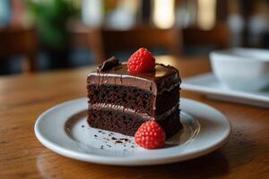 Closeup chocolate cake with fresh raspberry on white plate at the cafe photo