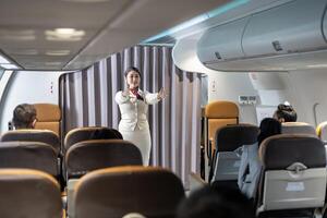 Flight attendant is demonstrating safety procedure showing emergency exit before taking off in the airplane for cabin crew and airline business photo