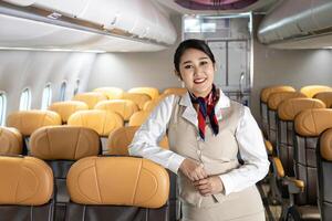 Asian flight attendant posing with smile inside aircraft for welcoming passenger on board with seat on the background for airline travel usage photo
