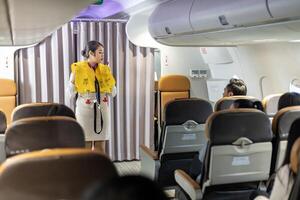 Asian flight attendant is demonstrating safety procedure using life jacket before taking off in the airplane for cabin crew and airline business photo