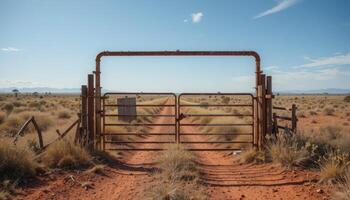 Rusty Gate at the Edge of a Desert Road Surrounded by Sparse Vegetation and Distant Mountains photo