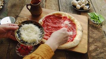 Making pizza. Female hands pouring grated cheese on dough. Preparing pizza with mushrooms and olives. video