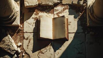 A historic open book resting upon a broken stone surface, surrounded by the remains of ancient civilization and touched by sunlight. photo