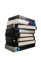 A tall stack of old VHS tapes with worn labels and cases, isolated on white back photo