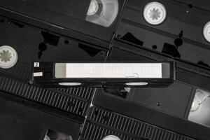 A collection of VHS tapes with one prominently displayed blank-labeled cassette. photo
