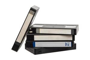 Stack of old VHS tapes with handwritten labels and visible wear, arranged casually on white back photo