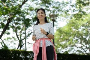 Wellness through yoga. Elderly woman enjoying outdoor exercise in park photo