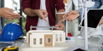 Hands-on Engineering Design. Team members analyzing sustainable building model with renewable energy features. photo