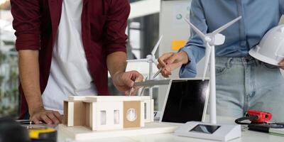 Engineer Collaboration on Sustainable Design. Team working on eco-friendly building model with wind turbines. photo