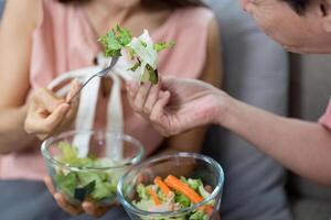 Wellness and Connection. Elderly couple sharing salad in a cozy home setting. photo