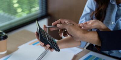 Financial Collaboration. Team members discussing calculations on a calculator during a business meeting. photo