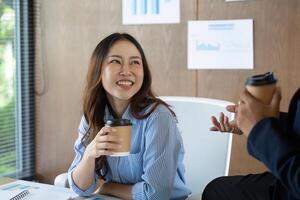 Positive Workplace Interaction. Smiling woman enjoying coffee while engaging in conversation with a colleague. photo