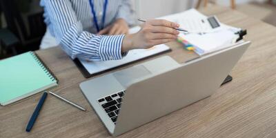 Remote Work and Digital Transformation. Businesswoman engaging in data analysis with laptop and documents. photo