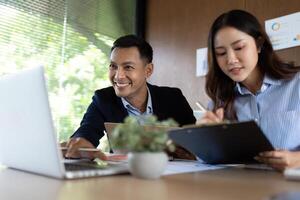 Collaborative Work Environment. Team members smiling while discussing project details on a laptop. photo