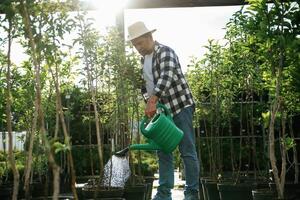 With watering can. Senior gardener is at work at daytime, photo