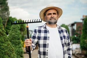 Standing with tools.,,, Senior gardener is at work at daytime photo
