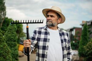 Standing, with tools. Senior gardener is at work at daytime photo