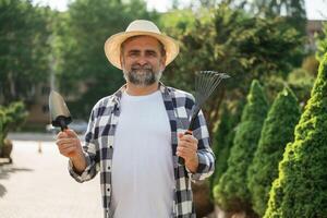 Standing with tools., Senior ,gardener is ,,at work at daytime photo