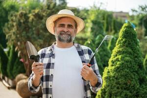 Standing, with, tools.. Senior gardener is at work at daytime photo