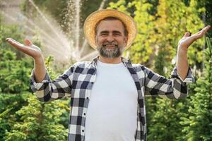 Against automatic watering machine. Senior gardener is at work at daytime photo