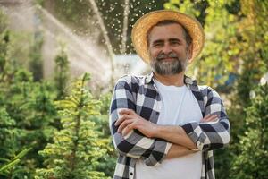 Against automatic watering machine.., Senior gardener is at work at daytime photo