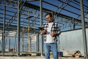 Wireless ,device,,, holding digital tablet in hands. Senior worker is near the unfinished greenhouse, working photo