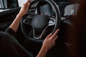 Focused close up view of woman hands that are driving new car. photo
