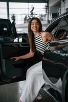 Going ,,out the door. Beautiful young woman is with new automobile in car showroom photo
