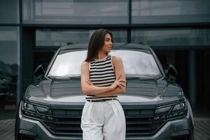 Attractive, young woman is outdoors near her brand new car photo