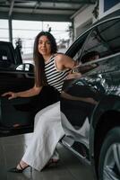 Going, out the door. Beautiful young woman is with new automobile in car showroom photo