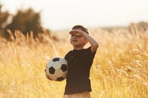 Holding soccer ball. Little boy, is ,having fun outdoors at summertime photo