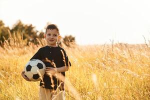 Holding soccer ball. Little ,boy is having fun outdoors at summertime photo
