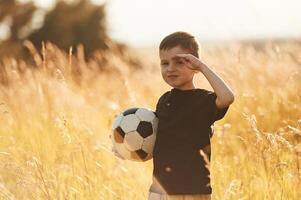 Holding soccer, ball. Little boy is having fun outdoors at summertime photo