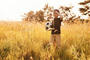 Holding ,,soccer ball. Little boy is having fun outdoors at summertime photo