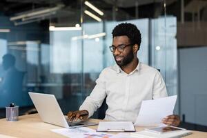 Successful businessman financier doing paperwork inside office, man preparing reports, and working with documents and papers. Company employee accountant, holding a contract in hands smiling happily. photo