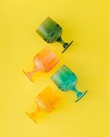 Colorful cocktail drinking glasses on bright yellow background. Minimal drink concept. Trendy summer party idea. Flat lay style. Top view. photo